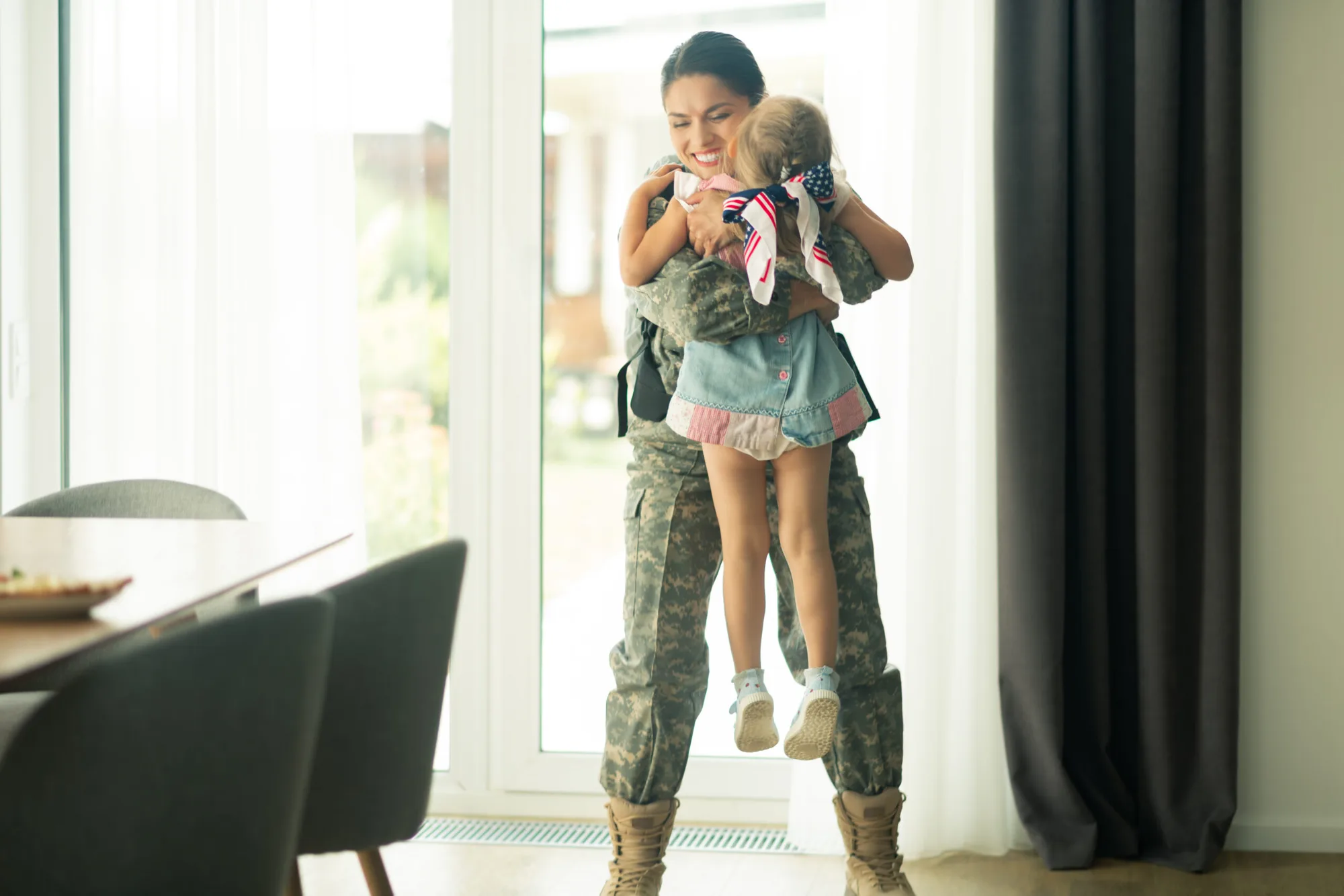 A servicewoman lifting and hugging her daughter at a homecoming reunion